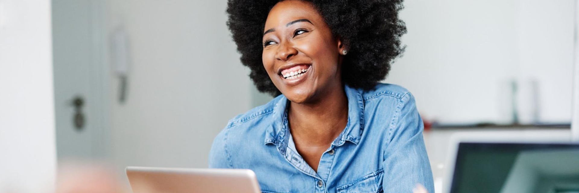 Happy teacher works on a laptop while smiling.