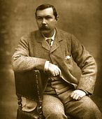 Sir Arthur Conan Doyle sitting sideways on chair