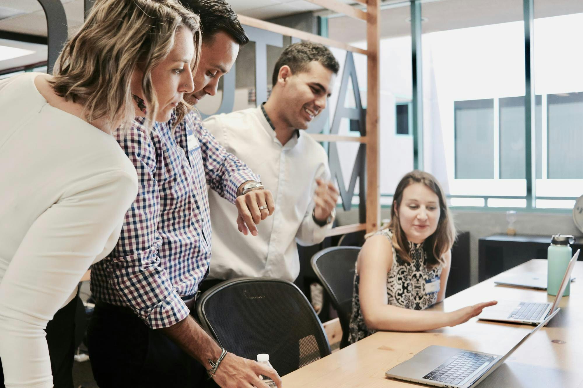 Teachers in a conference room look at laptop screens.