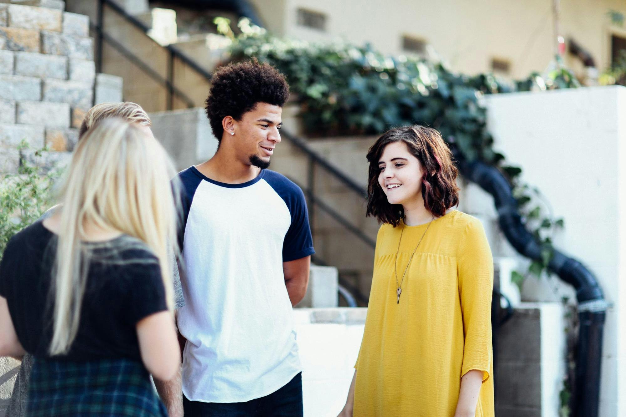 Three high school students talk outside in front of stone steps