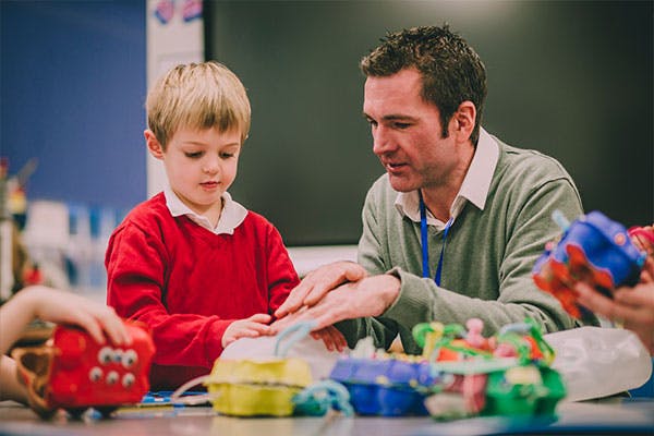 Teacher helping a young student with a creative and active learning activity.