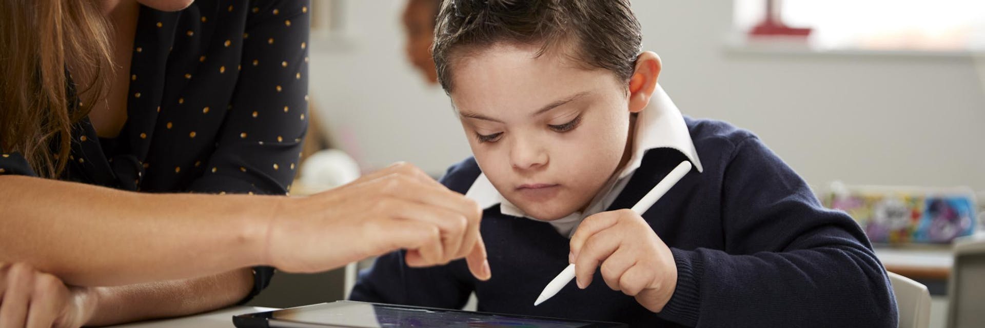 A teacher helps a student complete the Prodigy Placement Test on a tablet.