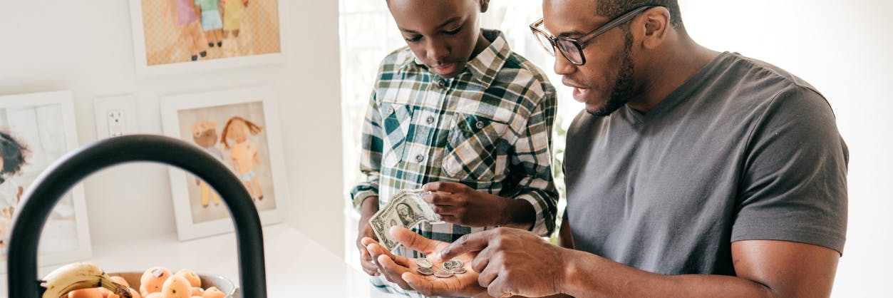 A father and son practicing counting skills using money.