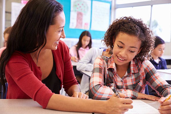 Teacher sitting with student in class.