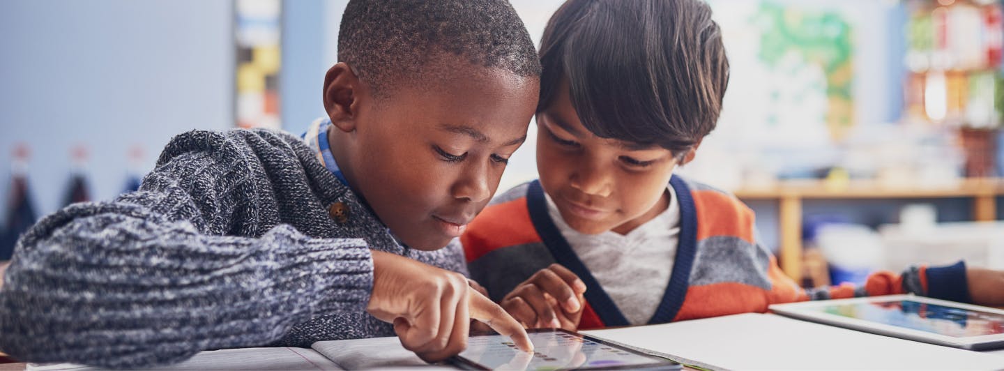 Students sharing a tablet in classroom.