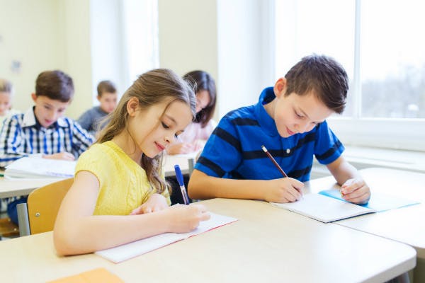 A classroom of young students writing.