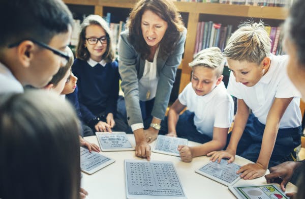 Teacher leading a group of students in a classroom activity.