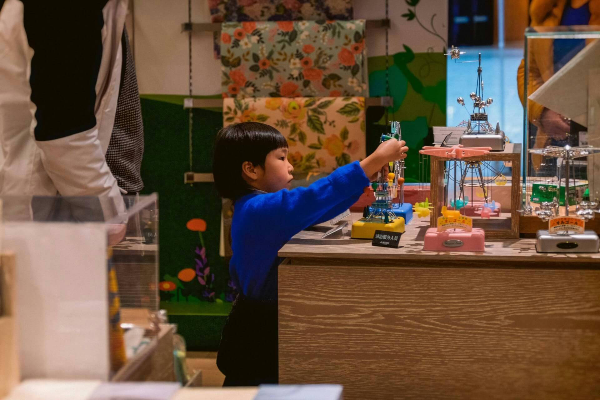 A young child plays with miniature carnival rides, an example of game-based learning.