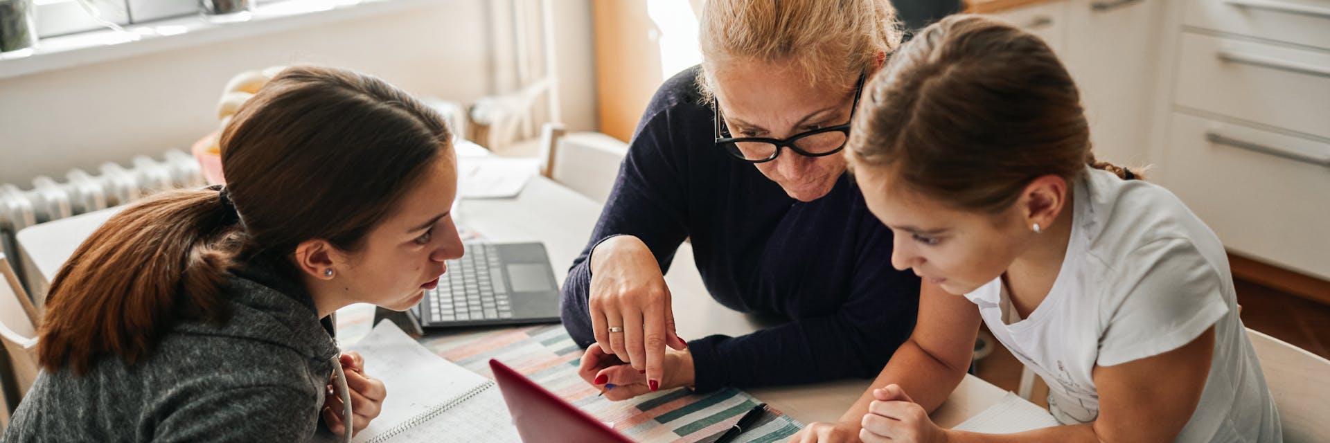 Two parents homeschooling their child at a table.