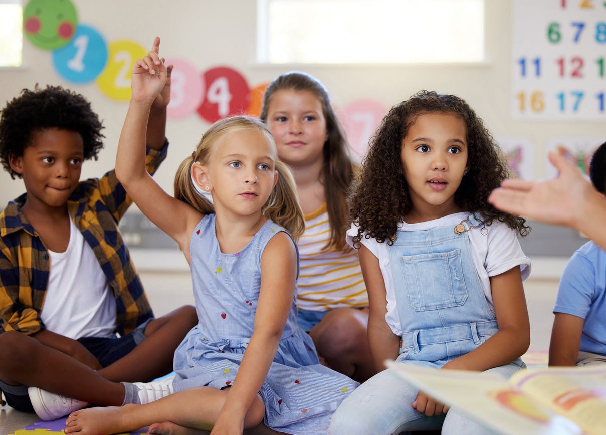 A small group of primary students participating in a class discussion during carpet time.