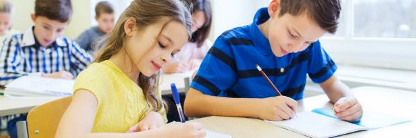 A classroom of young students writing.