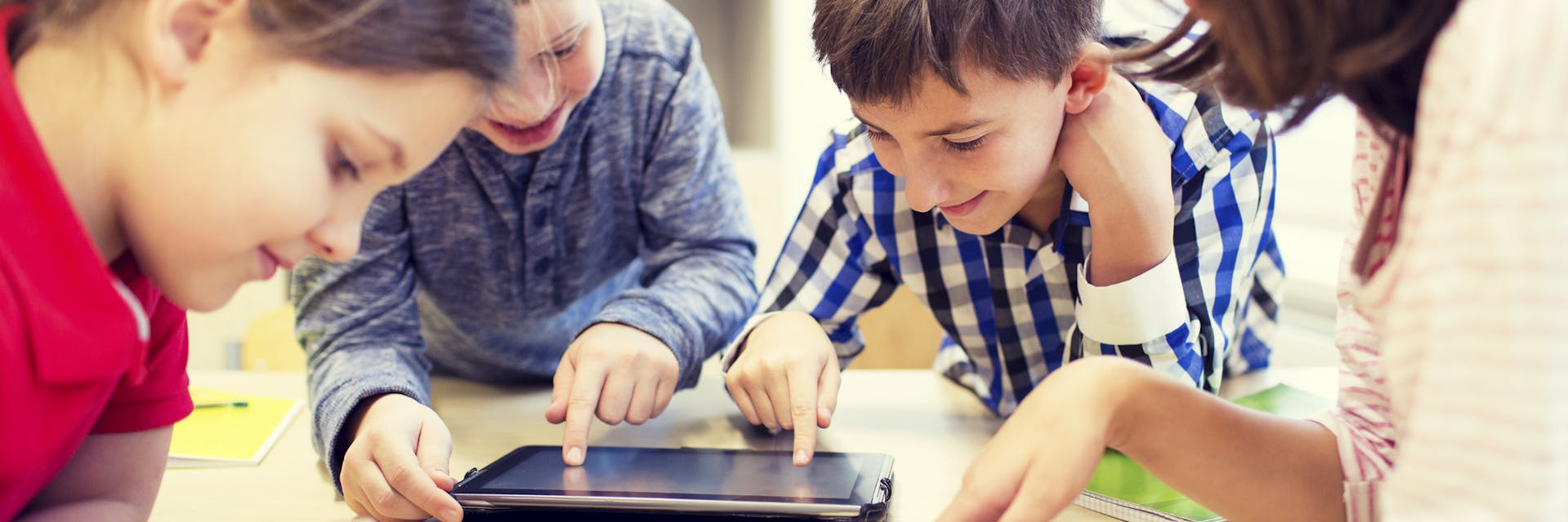 Students using a tablet together in a blended learning environment.