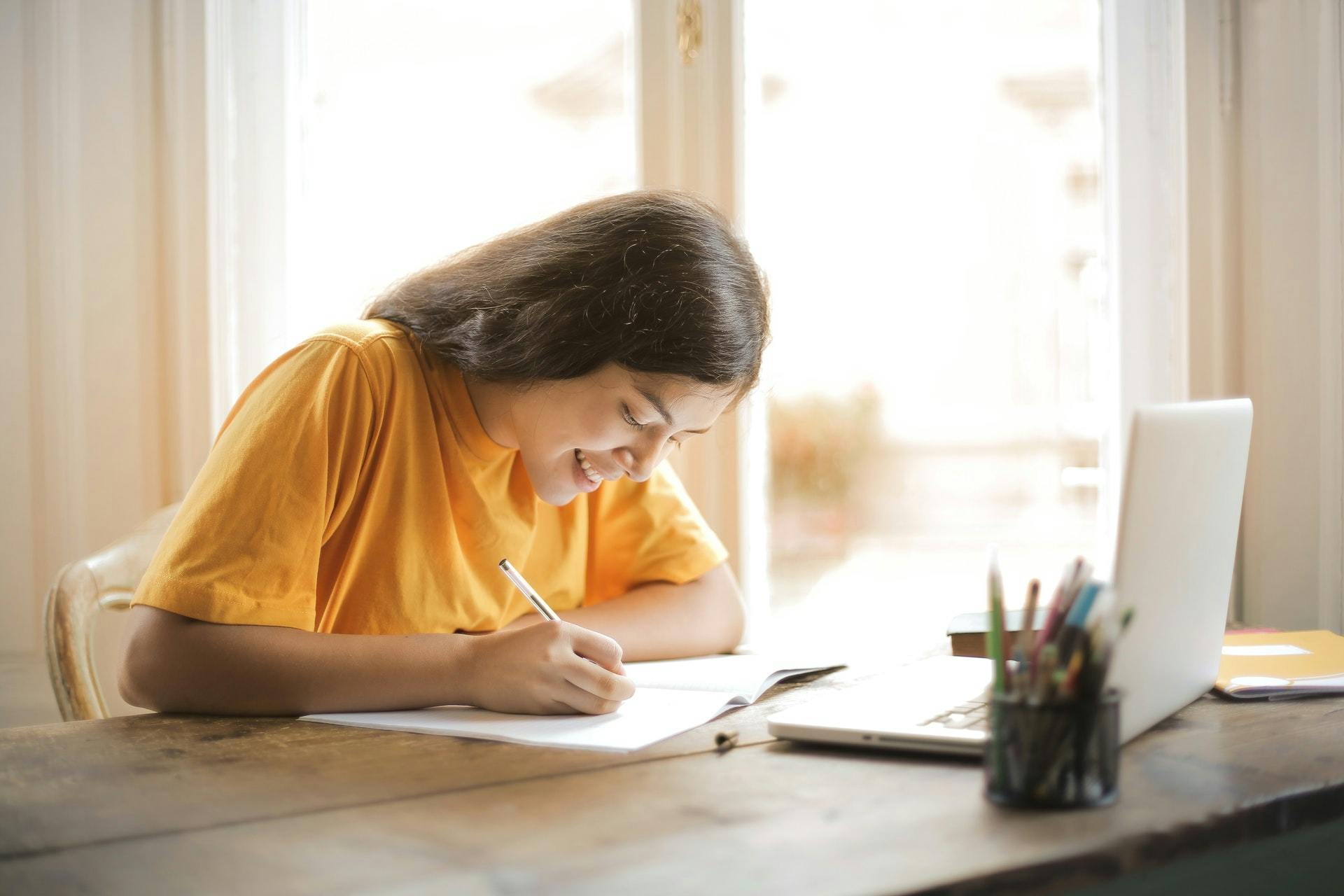 A student in a yellow shirt sits at a table and studies.