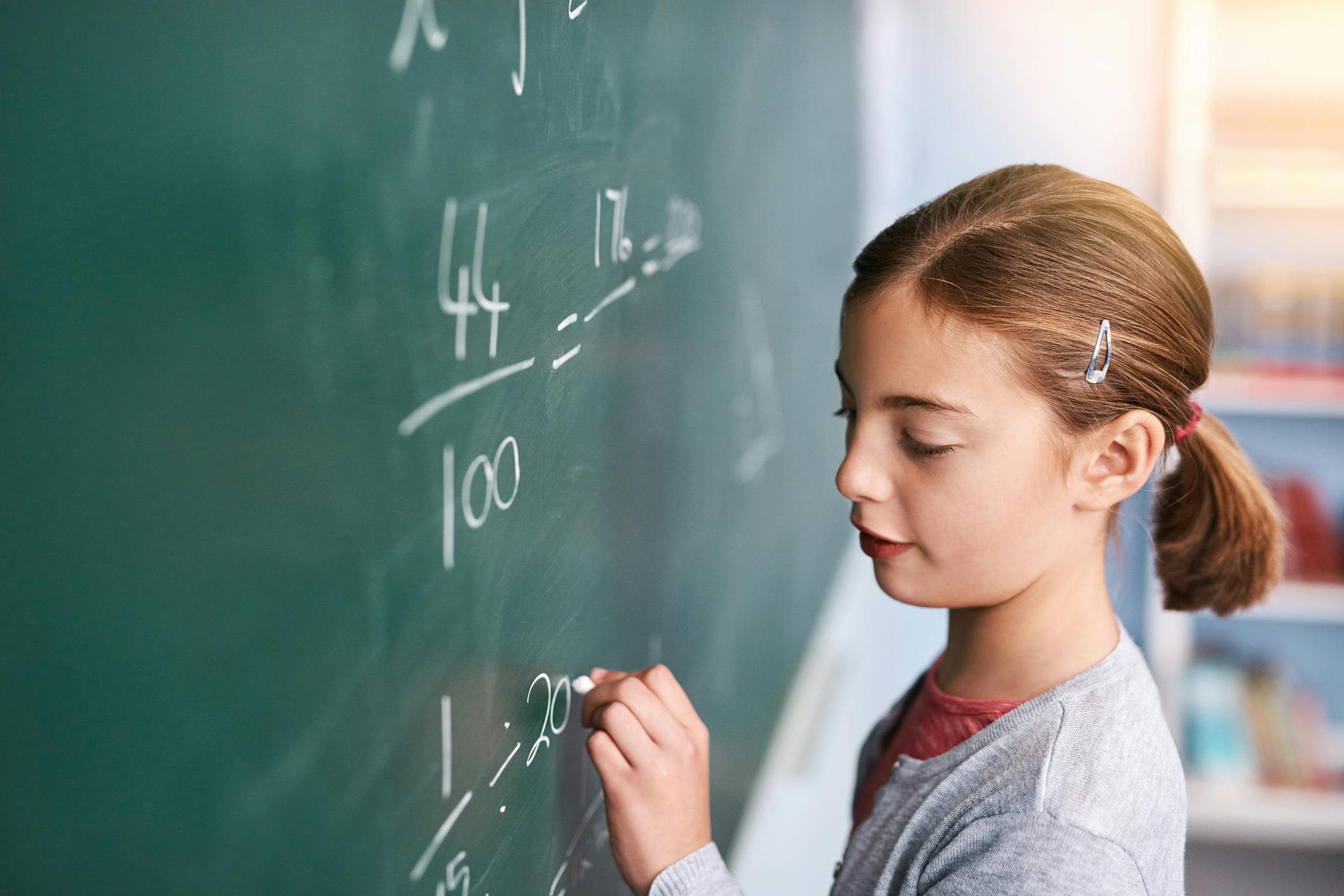 Child writing equations on a blackboard