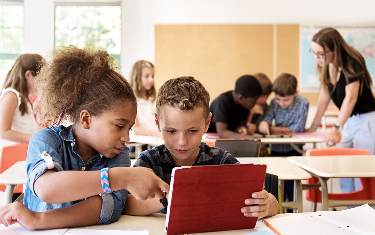 School kids in class using a digital tablet during student-centered learning time.