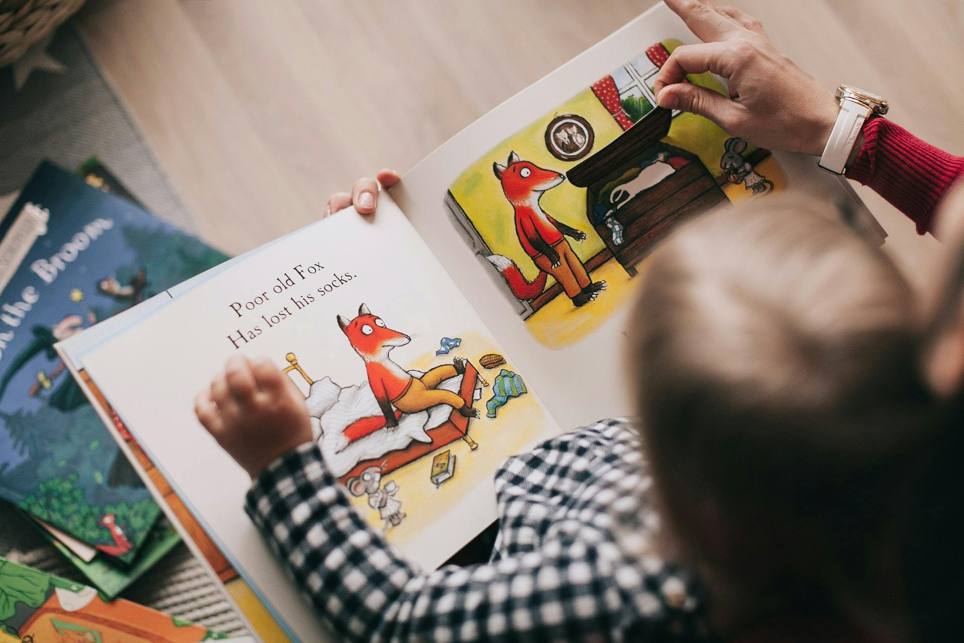 Overhead picture of a young child reading a book in a play-based learning classroom. 