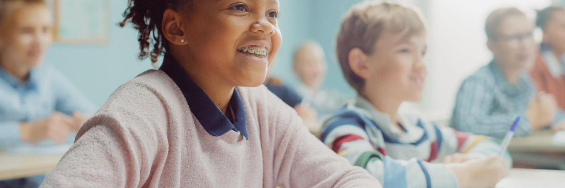 Child smiles in math class while teacher makes math fun