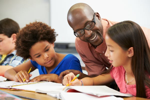 A teacher supporting two students with an in-class assignment.